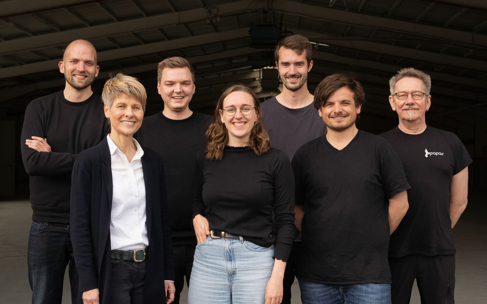 Das Team aus sieben Personen des Startups Papair aus Hannover steht vor der Produktionshalle in Rethem und lächelt in die Kamera